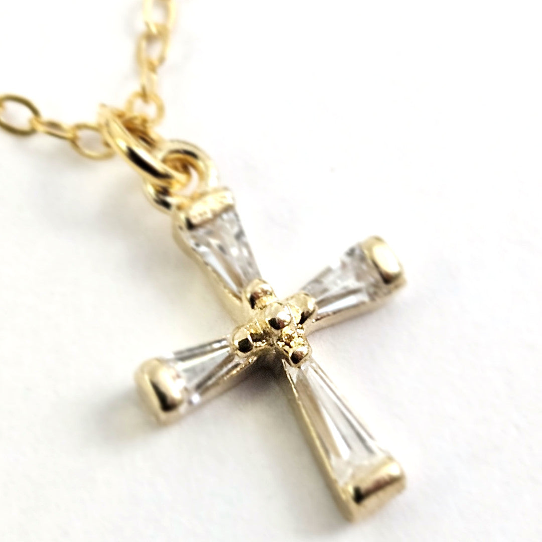 Gold cross pendant necklace on a white background