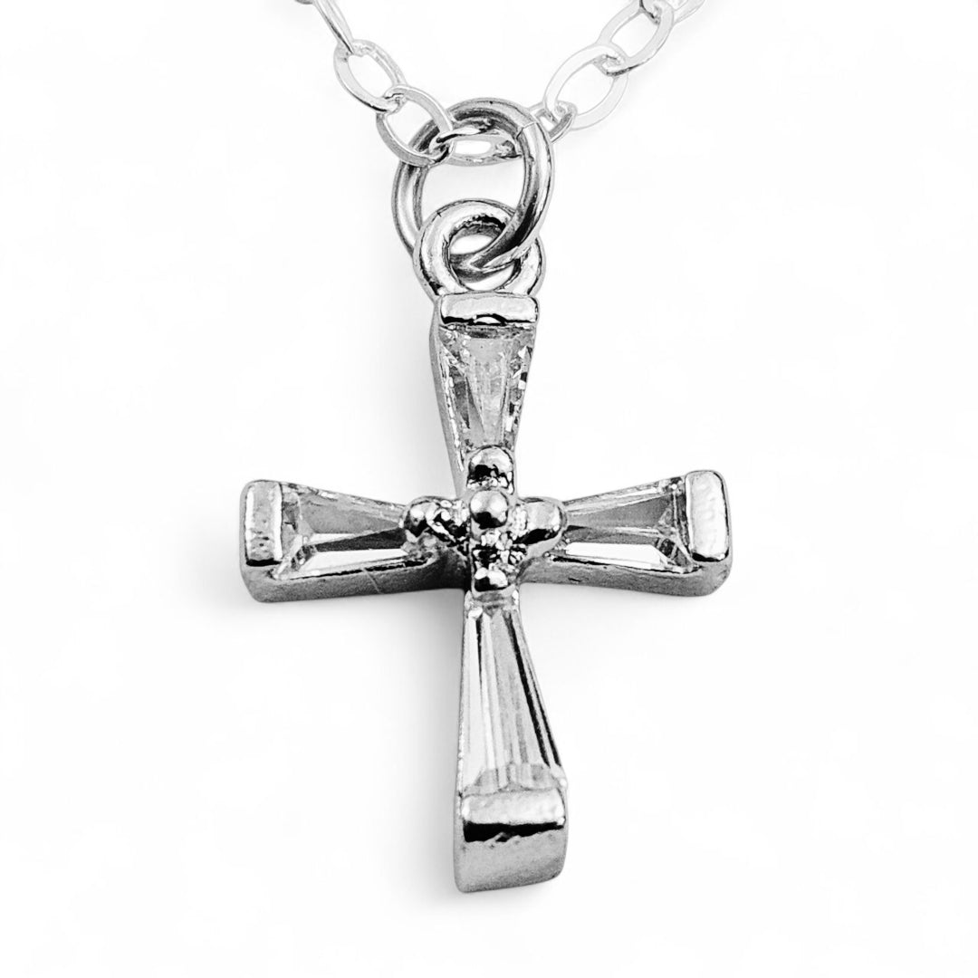 Silver cross pendant on a chain against a white background